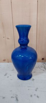 un vase en verre bleu posé sur une table blanche