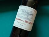 une bouteille de vin posée sur une table de billard, à côté d'une queue de billard