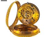 a gold pocket watch that is open on a white surface
