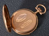 a gold pocket watch on a black surface with a name engraved on it