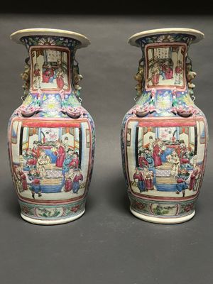 pair of chinese vases sitting on a gray surface with a black background
