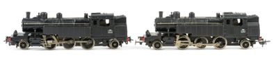 two black trains sitting side by side on a white surface