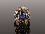 a close up of a ring with a blue sapphire and white diamonds