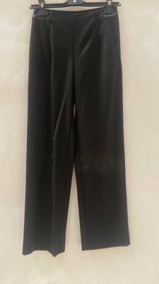 a black leather pants hanging on a hanger on a wall