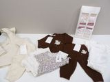 a pile of baby clothes on a table next to a bag of diapers