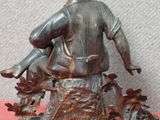 statue représentant un homme assis sur une souche d'arbre, coiffé d'un chapeau