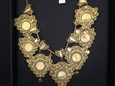 Un collier en or est exposé dans une vitrine noire