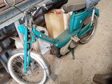 a blue motorcycle parked in a garage with a lot of junk on the floor