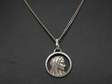 a silver pendant with a woman ' s face on a chain
