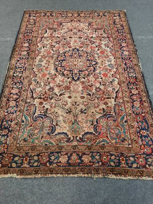 Un tapis persan ancien est posé sur le sol d'une pièce.