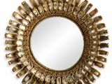 un miroir rond avec un cadre doré et un motif décoratif tout autour