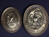 two silver coins with the image of a man and a woman on them