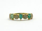 a close up of a yellow gold ring with green stones