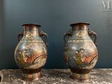 two vases are sitting on a table with a blue wall in the background