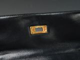 black leather purse with a gold buckle on a black background