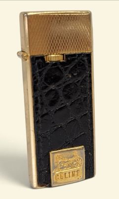 une image représentant un briquet noir et doré posé sur une surface blanche