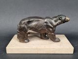 sculpture en bronze représentant un ours, posée sur un socle en marbre, sur un fond gris