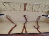 a brown suitcase with leather handles and straps