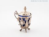 an antique silver and blue cup with a lid on a stand