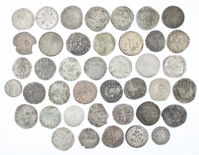 an assortment of old silver coins on a white surface