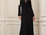 une femme en robe noire, debout dans une pièce