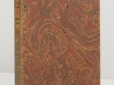 an old book with a marbled cover on a white surface