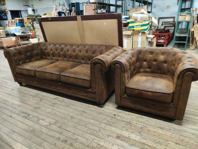pair of brown leather chesterfield sofas in a warehouse setting