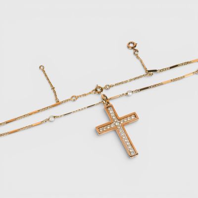un collier en or avec une croix et une chaîne sur fond blanc