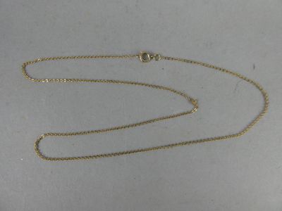 gros plan d'un collier en or avec une chaîne sur une surface blanche