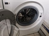 a washing machine that is sitting next to a trash can