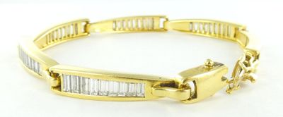 un gros plan sur un bracelet en or orné de pierres taillées en baguette