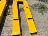deux morceaux de métal jaune posés par terre près d'un buisson