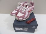 pink new balance shoes with white laces on top of a box