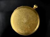 gold plated pocket watch on a black background