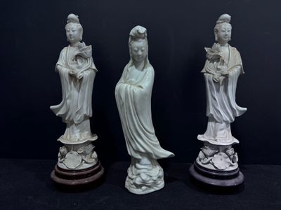 trois statues blanches représentant des femmes asiatiques, posées sur des socles, sur fond noir