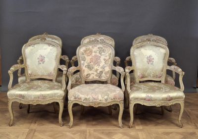 four antique chairs are lined up against a wall in a room