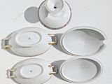 four white bowls and a teapot on a white table