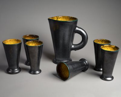 quatre tasses et un pichet posés sur une table