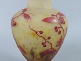 a yellow vase with red flowers on it sitting on a table