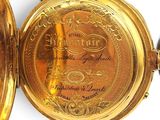 a gold pocket watch that is open on a white surface