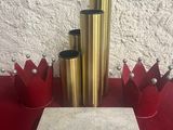 une table rouge sur laquelle sont posés des vases dorés et une boîte blanche