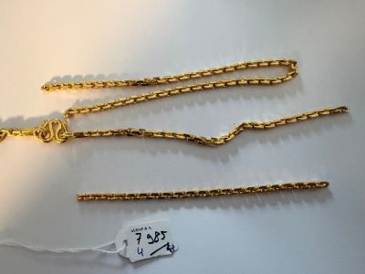 a close up of three gold chains on a white surface