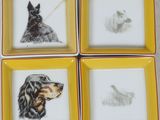 quatre assiettes carrées sur lesquelles sont dessinés des chiens, posées sur une table