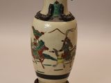 a vase with a painting on it sitting on a table