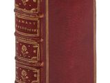 un vieux livre avec une couverture rouge et des bordures dorées sur fond blanc