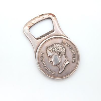 a bottle opener with a coin on it on a white surface