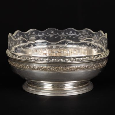 un plat ancien en argent avec un bol en verre sur fond noir