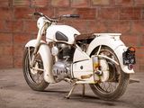 a white motorcycle that is parked in front of a brick wall