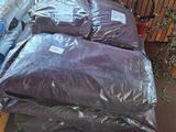 a pile of bags of pillows on a pallet next to a potted plant