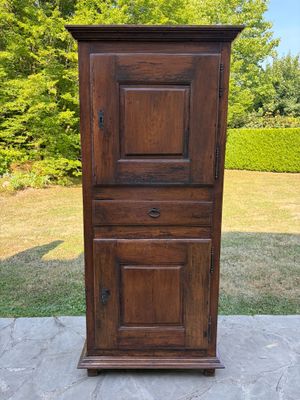 une vieille armoire en bois posée sur une terrasse, à côté d'une pelouse